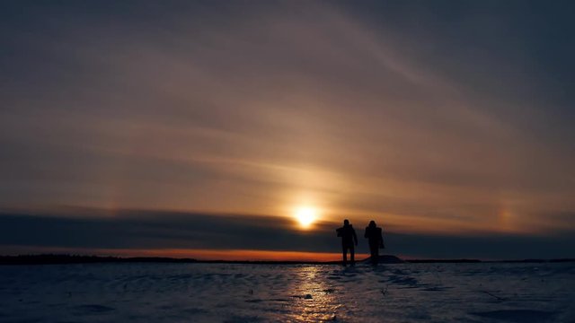 two tourists silhouette men go to sunset travelers. tourism concept two people photographers walking through the snow outdoors winter sunset sunlight cold beautiful landscape silhouette