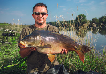 Obraz premium Happy angler with carp fishing trophy