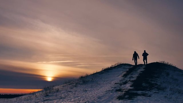 people winter silhouette does selfie photograph joy snow sunlight. group of tourists walking on top of a sunset silhouette mountain. slow video tourists people group go lifestyle travel nature