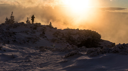 Young photographer taking pictures of a foggy sunrise in the mountains in Romania