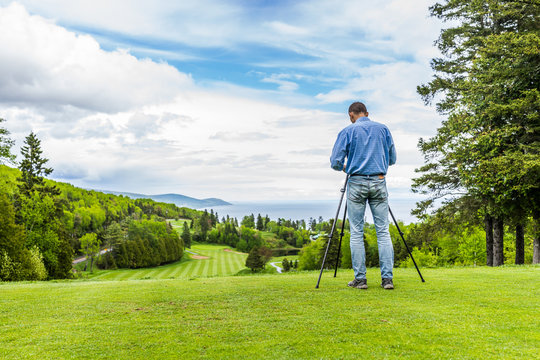 Landscape view of green golf course with hills in summer in La Malbaie, Quebec, Canada in Charlevoix region with photographer and tripod, profession