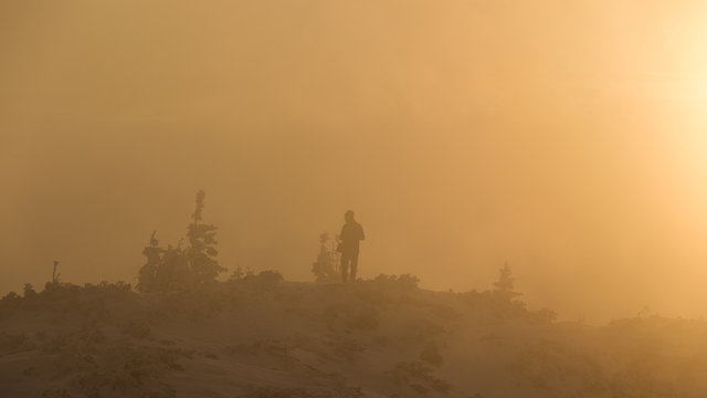 Young photographer taking pictures of a foggy sunrise in the mountains in Romania
