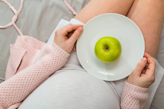 Pregnant woman eating apple. Aerial close up view.