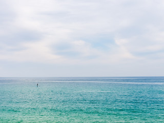 Obraz premium Silhouette of a lonely rower standing up on paddle board in the blue sea. Israel, Tel-Aviv