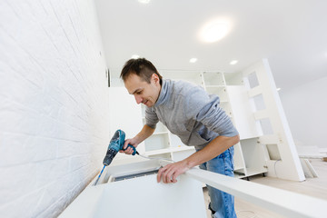 Man assembling kitchen cupboard using screwdriver