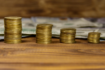 Stacks of golden coins and dollar bills on wooden background