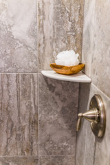 Closeup of staging shower pouf brush in modern stone grey bathroom with dial in model home, apartment or house