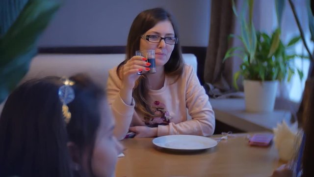 the woman is sitting in a cafe and drinking from a glass goblet. woman is eating a slow-motion video indoors in the cafe