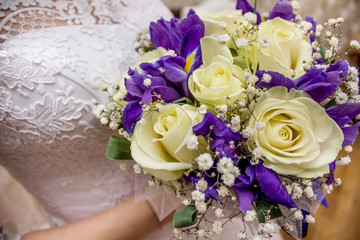 Bride is holding a wedding bouquet and a glass of champagne