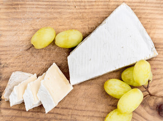 Creamy Brie on rustic  cutting board over white wooden background, © nataliazakharova