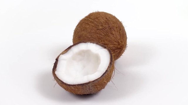 One ripe whole brown tropical coconut and a half with yummy white pulp rotating on white isolated background. Healthy fresh tropical fruits. Loopable seamless cocos rotating
