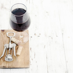  A glass of red wine, corkscrew  and wine corks on rustic white wooden background
