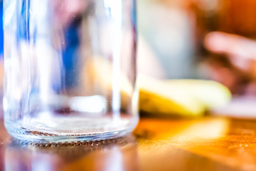 Macro closeup of empty glass bottle with clear transparent reflection surface low angle level on wooden table