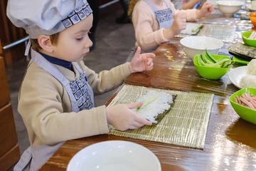 Foto op Canvas Cooking of traditional sushi rolls. The boy is dressed as a cook. © bravissimos