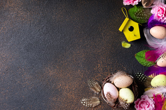 Easter background. Easter composition: eggs, nest with eggs, flowers, feathers and easter decorations on aged stone background. Top view, copy space