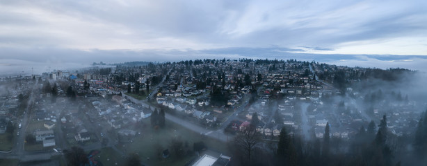 Aerial panoramic view of the residential neighborhood in the city during a foggy sunrise. Taken in New Westminster, Greater Vancouver, British Columbia, Canada.