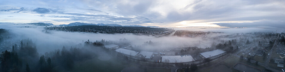 Aerial panoramic view of the residential neighborhood in the city during a foggy sunrise. Taken in New Westminster, Greater Vancouver, British Columbia, Canada.