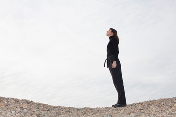 lone young woman standing on pebbles and enjoying the sun