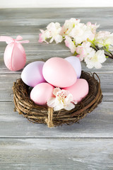 Perfect colorful handmade easter eggs in a nest with spring flowers on a wooden gray background. Happy Easter