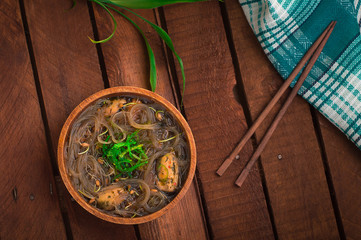 Japanese cuisine, soup with chashu pork, chives, sprouts, noodles and seaweed on the table under the sunlight. Wooden rustic background. Top view