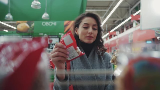 Portrait woman chooses nuts in a supermarket think shopaholic girl shopping buy customer shopper store mall , healthy product health retail family young beautiful female happy hypermarket slow motion