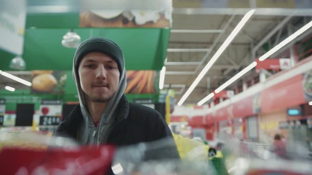 Portrait man steals nuts looks around and go away in supermarket shoplifting larceny technology crime store theft criminal customer illegal poor looting poverty lifting security shop consumer