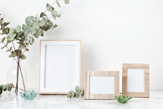 Three frames mockup, front view, with decor elements, flowers and blank copy space over the white wall.