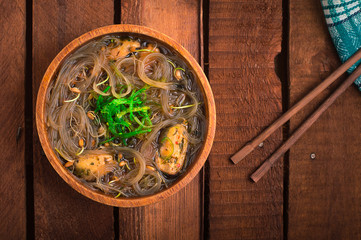 Fototapeta na wymiar Japanese cuisine, soup with chashu pork, chives, sprouts, noodles and seaweed on the table under the sunlight. Wooden rustic background. Top view