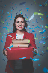 Beautiful happy woman with gift box at celebration party with confetti . Birthday or New Year eve celebrating concept