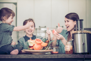 Mom with children in the kitchen prepares juice fresh