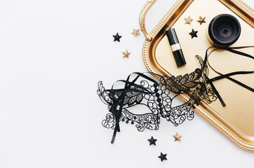 Flat Lay with Black venetian mask, gold tray, lipstick on white background. Sexy Female Accessories