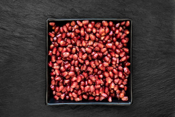 Pomegranate Seeds in the Black Plate Which Placed on Black Stone Background Surface