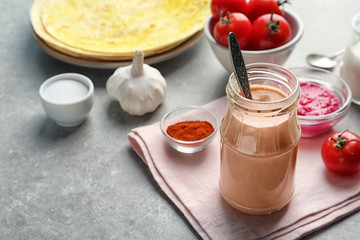 Jar with tasty creamy tomato sauce for fish taco on table