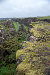 Thingvellir, Iceland - July 19, 2017: Tourists walk through the Almannagja fault line in the mid-atlantic ridge north american plate in Thingvellir National Park. Iceland