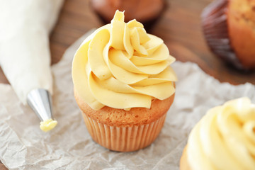 Tasty cupcake with cream on table