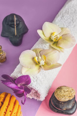 Beautiful orange handmade soap and towel with Orchid flowers for Spa treatments on two-tone background. Incense stick.