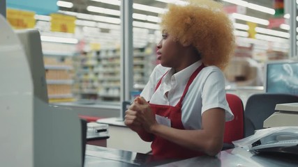 Portrait african american woman blond hair works at supermarket cash desk serious girl fruit technology grocery market store customers black retail indoors consumer vegetables fresh slow motion - Powered by Adobe