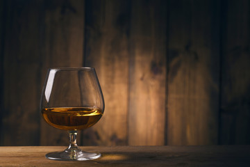 Glass of cognac on the wooden table