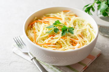 Fresh coleslaw salad in bowl on gray stone background.
