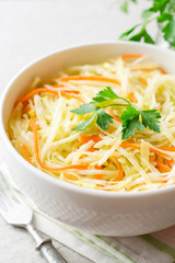 Fresh coleslaw salad in bowl on gray stone background.