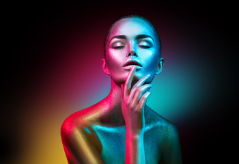 Fashion model woman in colorful bright sparkles and neon lights posing in studio, portrait of beautiful sexy girl. Art design colorful vivid makeup