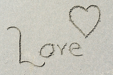 Love and heart etched into ocean beach sand. Romantic message in a seaside setting. Wedding, anniversary or engagement, romance at the beach.