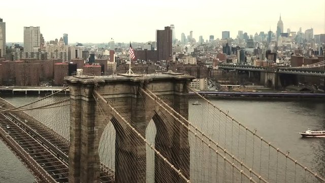 Brooklyn Bridge with American flag - aerial moving toward Manhattan skyline in New York City NYC in 1080 HD