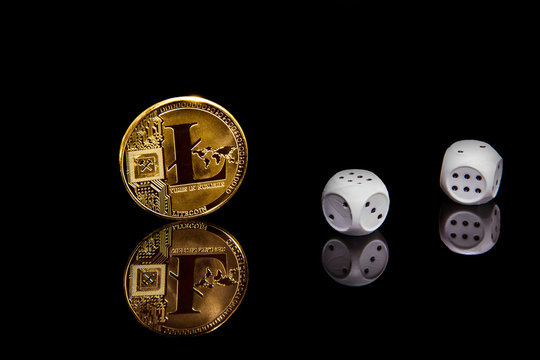 Conceptual picture of gold cripto currency litecoin coin on black mirror surface next to dice