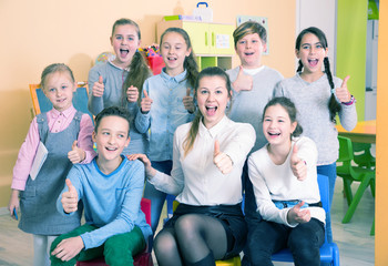 Pupils with teacher giving thumbs up in schoolroom