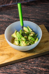 Cooking traditional latin american mexican sauce guacamole in a bowl with avocado, making guacamole in the kitchen, guacamole recipe.