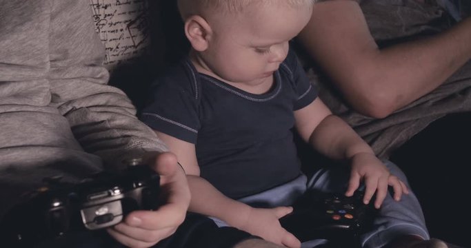 Guys and baby boy play video game console, have fun, laugh, hold joystick.