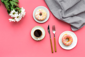 modern breakfast desing with sweet donut, coffee and flowers on woman pink desk background top view mock up