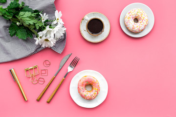 modern breakfast desing with sweet donut, coffee and flowers on woman pink desk background top view mock up