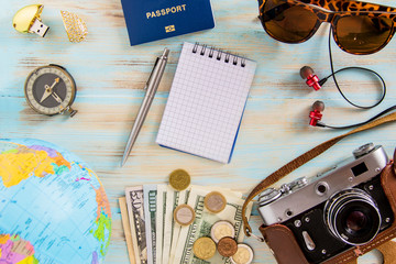 Conceptual tour planing image of travelling accessories on blue wooden background